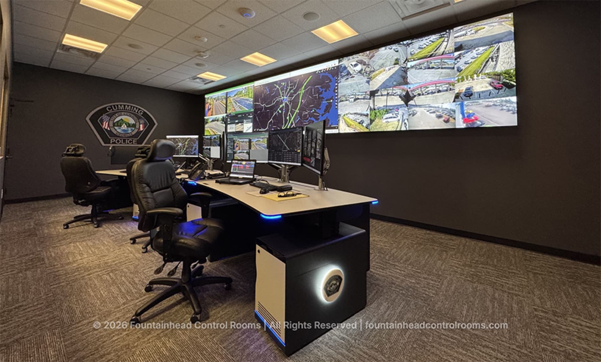 Cumming Police real-time crime center with dual-operator consoles and a video wall of maps and camera feeds