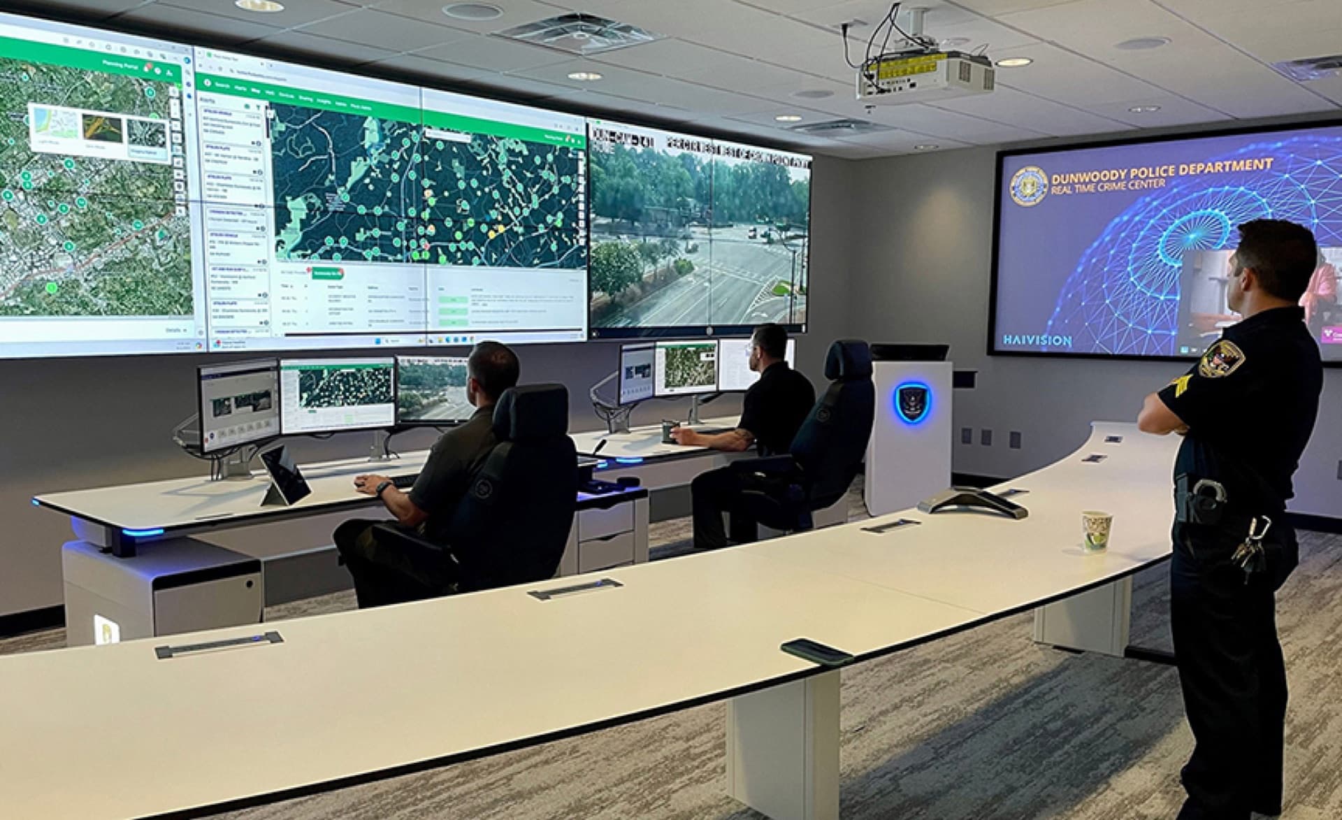 Operators working at curved dispatch consoles in the Dunwoody Police Real Time Crime Center
