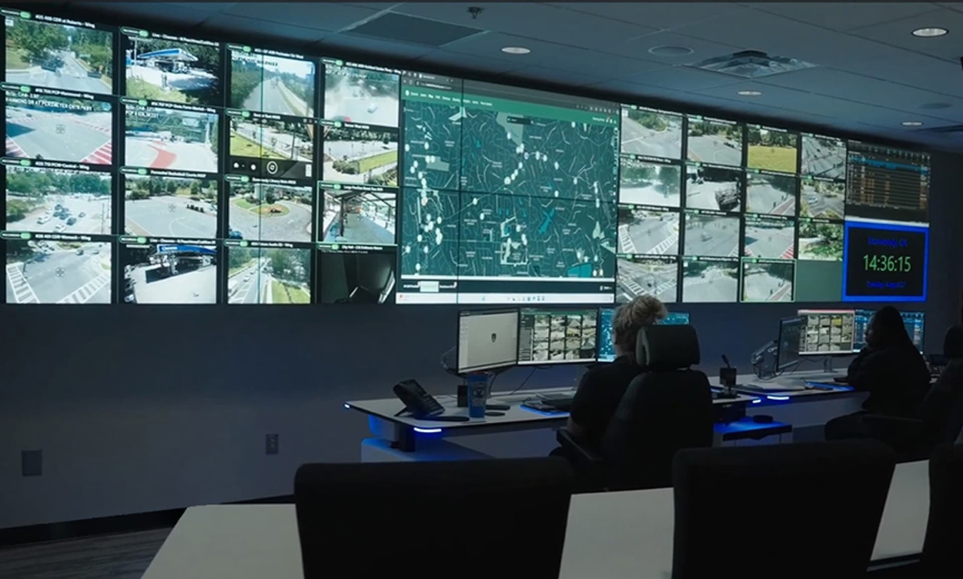 Dunwoody Police real-time crime center with operators at consoles facing a large video wall of live traffic camera feeds